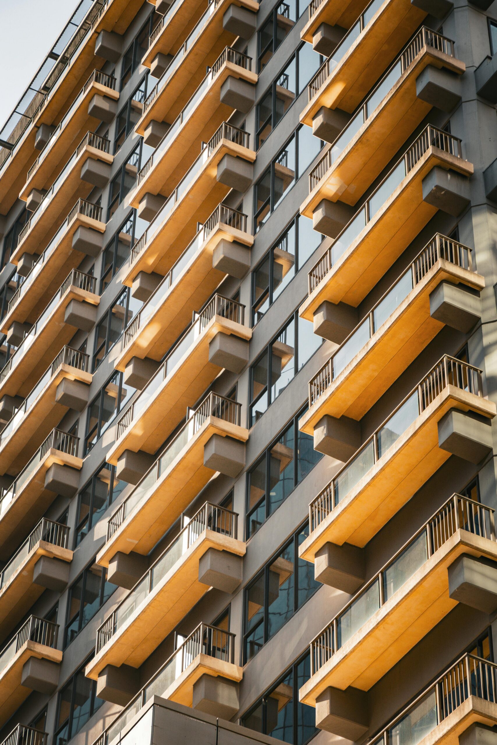 Angled view of a modern apartment building with multiple balconies bathed in sunlight.